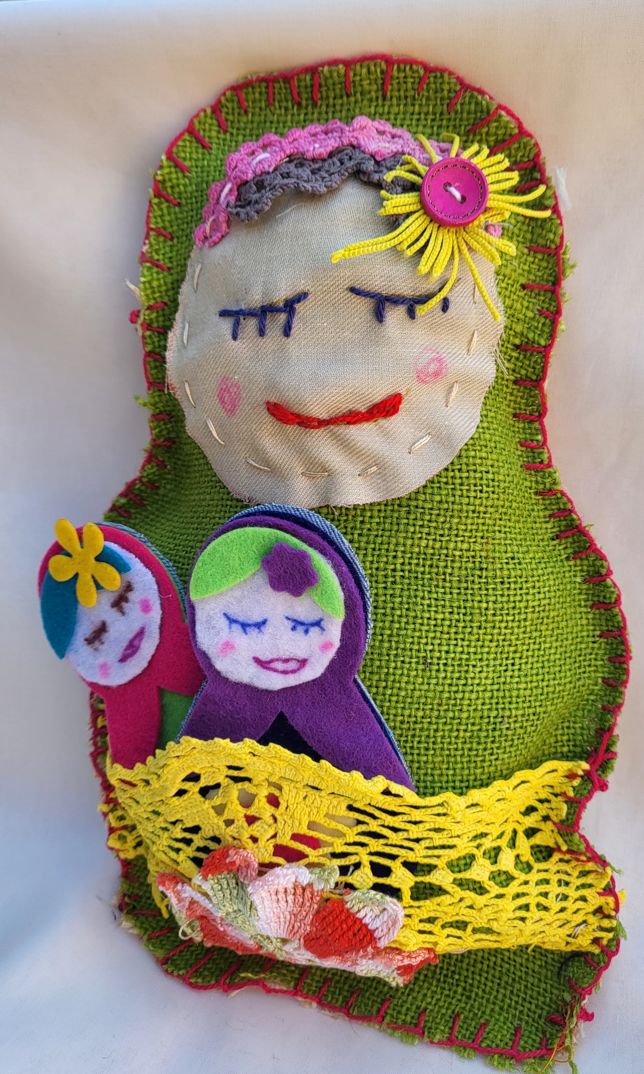 Colourful hand sewn Babushka doll, eyes closed, smiling.