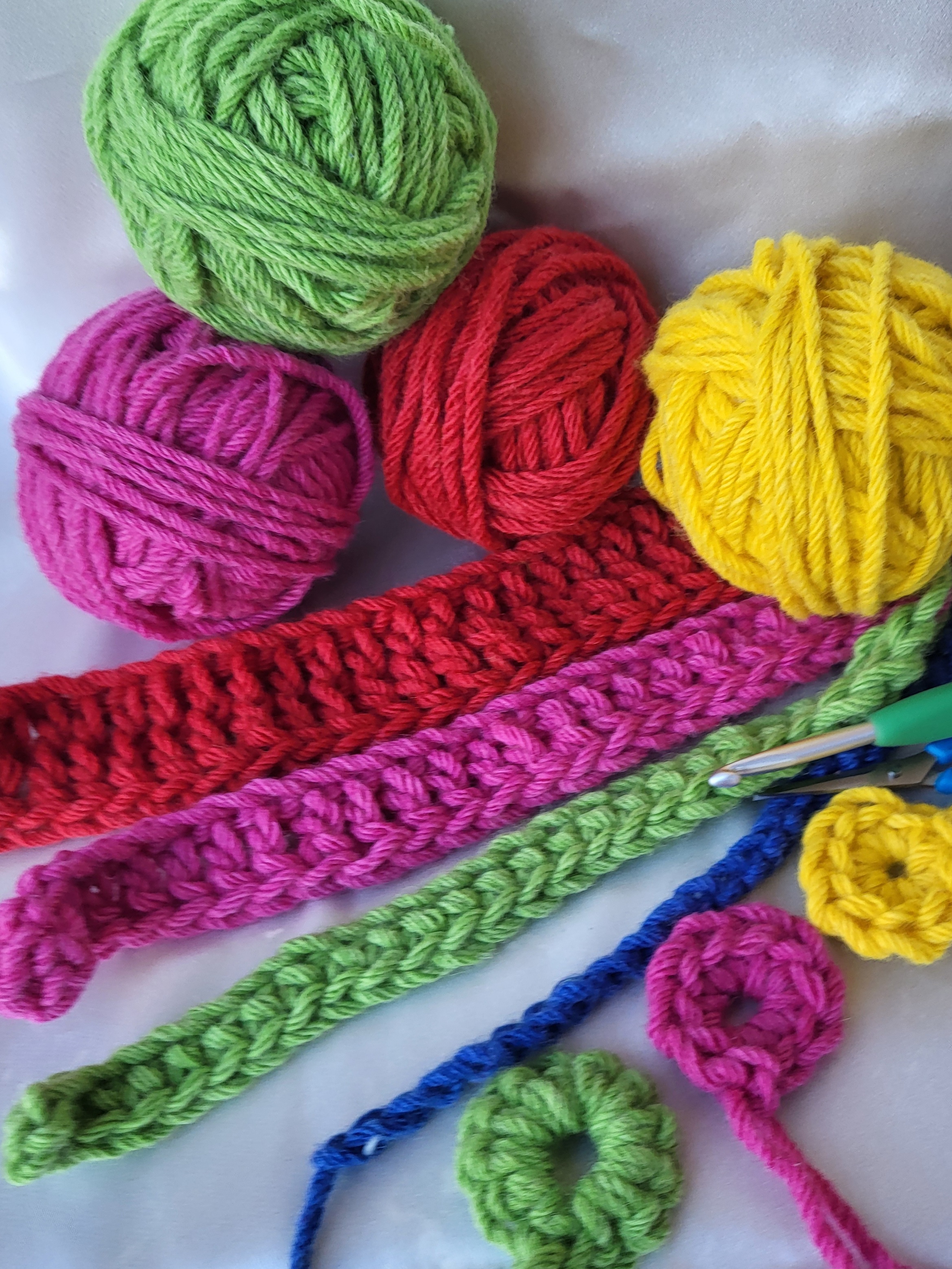Coloured balls of yarn, yellow, pick, green and red. With examples of crochet.