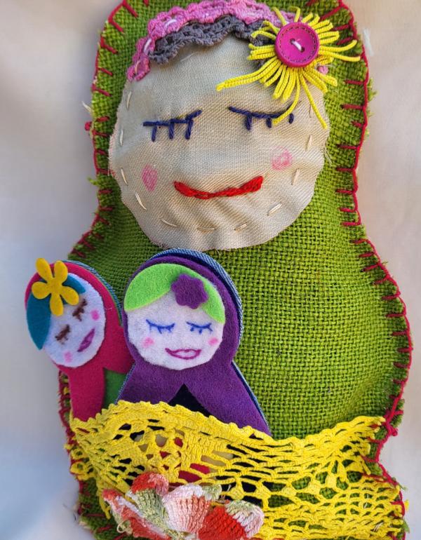 Colourful hand sewn Babushka doll, eyes closed, smiling.