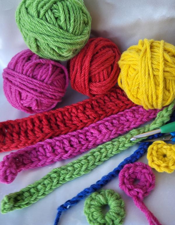 Coloured balls of yarn, yellow, pick, green and red. With examples of crochet.