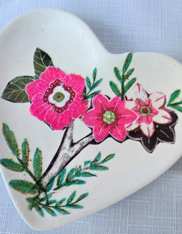 White heart shaped trinket dish with pink flowers and green leaves.