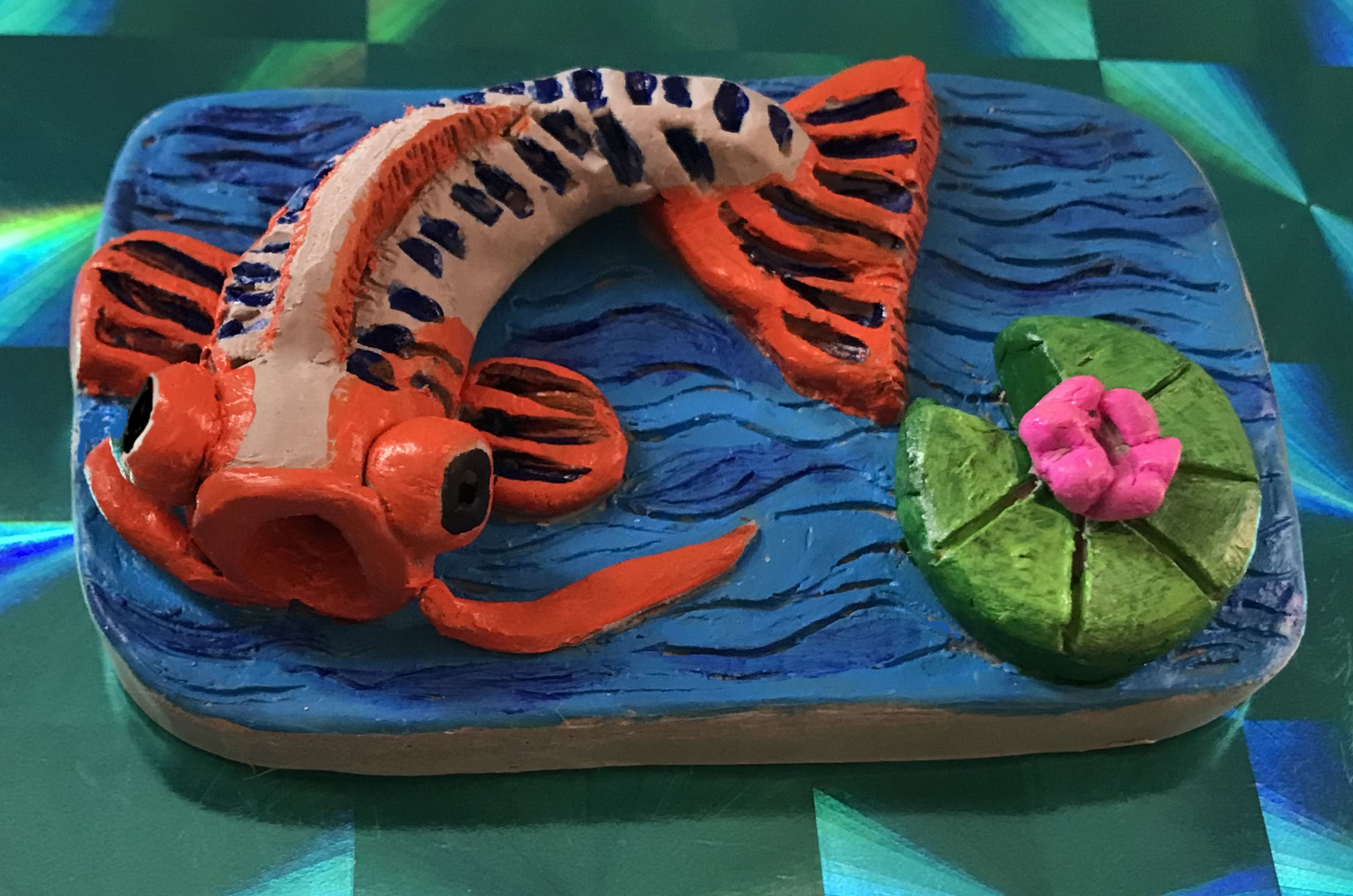 Orange fish on blue background made of clay