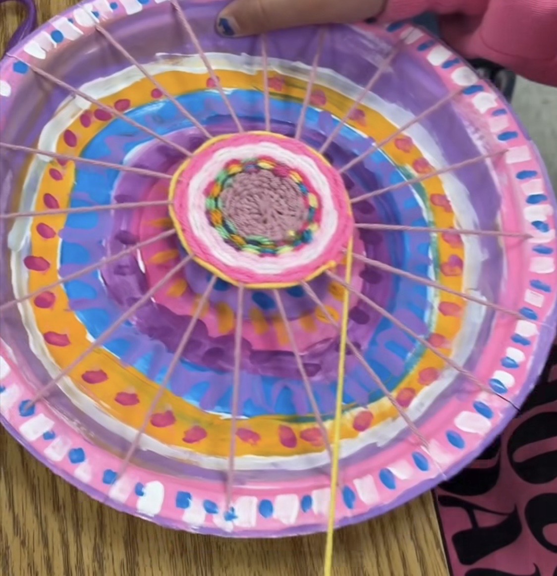 Paper plate with wool woven across it 