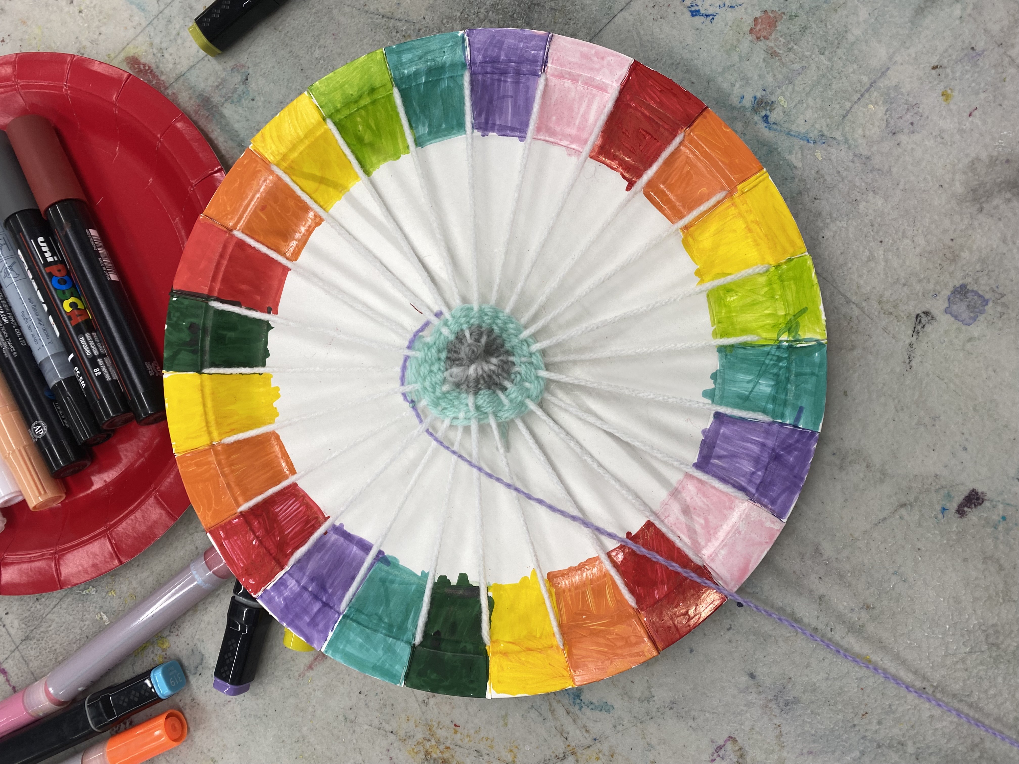 A paper plate with coloured edges used for weaving in a spiral pattern.