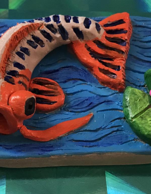 Orange fish on blue background made of clay