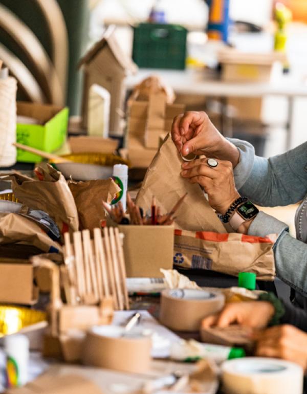hands creating houses out of cardboard