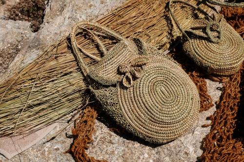 Two woven bags lying on a bed of rock and reeds