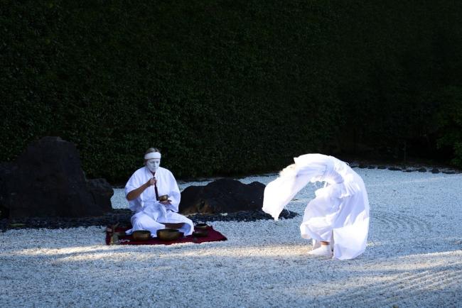 Two people in white outfits in a drystone pebble garden